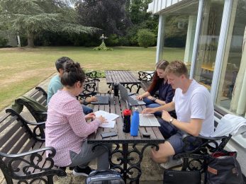 Students working in the grounds of Clare Hall, University of Cambridge